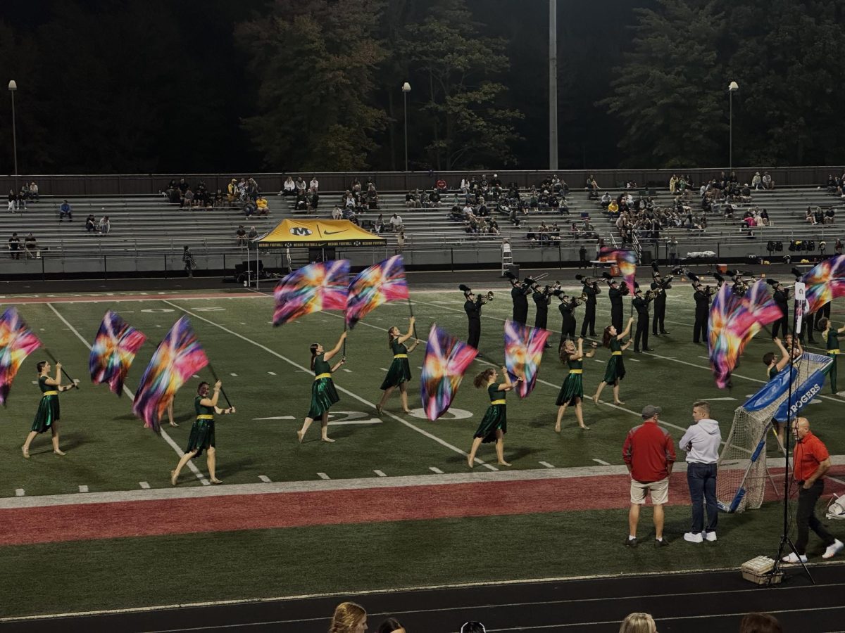 Medina color guard displays vibrant flags on the field during halftime.