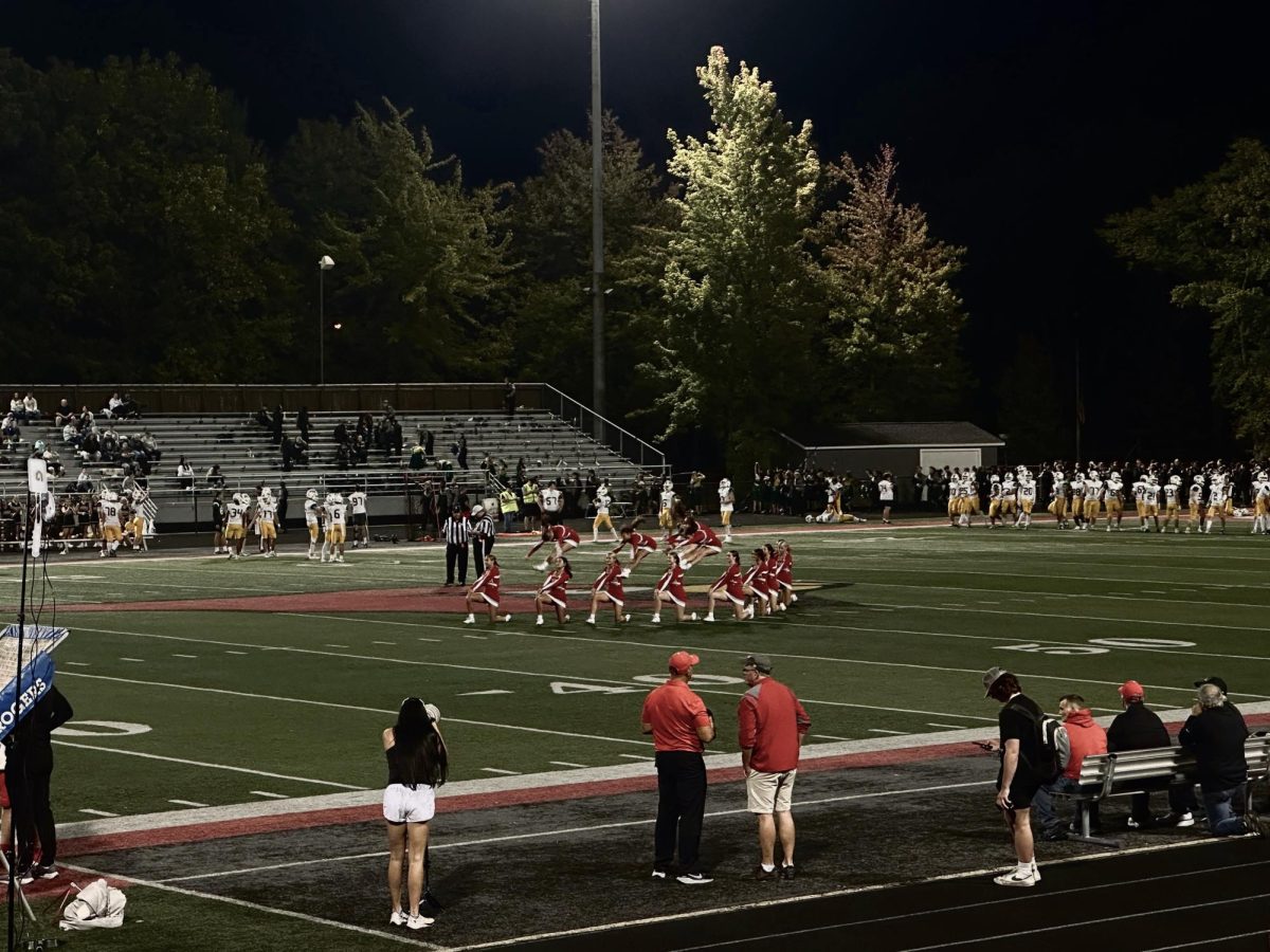 Mentor cheerleaders hitting a V formation as center performers execute pike jumps.